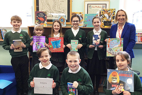 Helen hands books to children at a local school