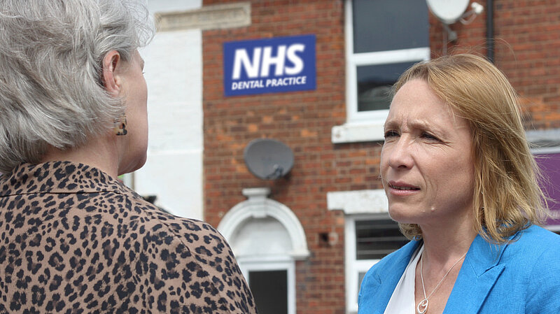 Helen talks to a resident outside a local dental practice